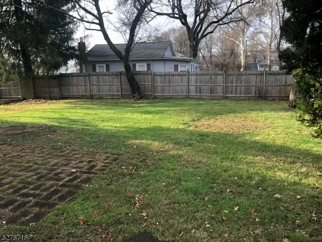 a view of a yard with a fence and trees