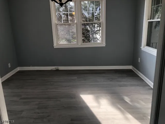 en empty room with wooden floor and windows