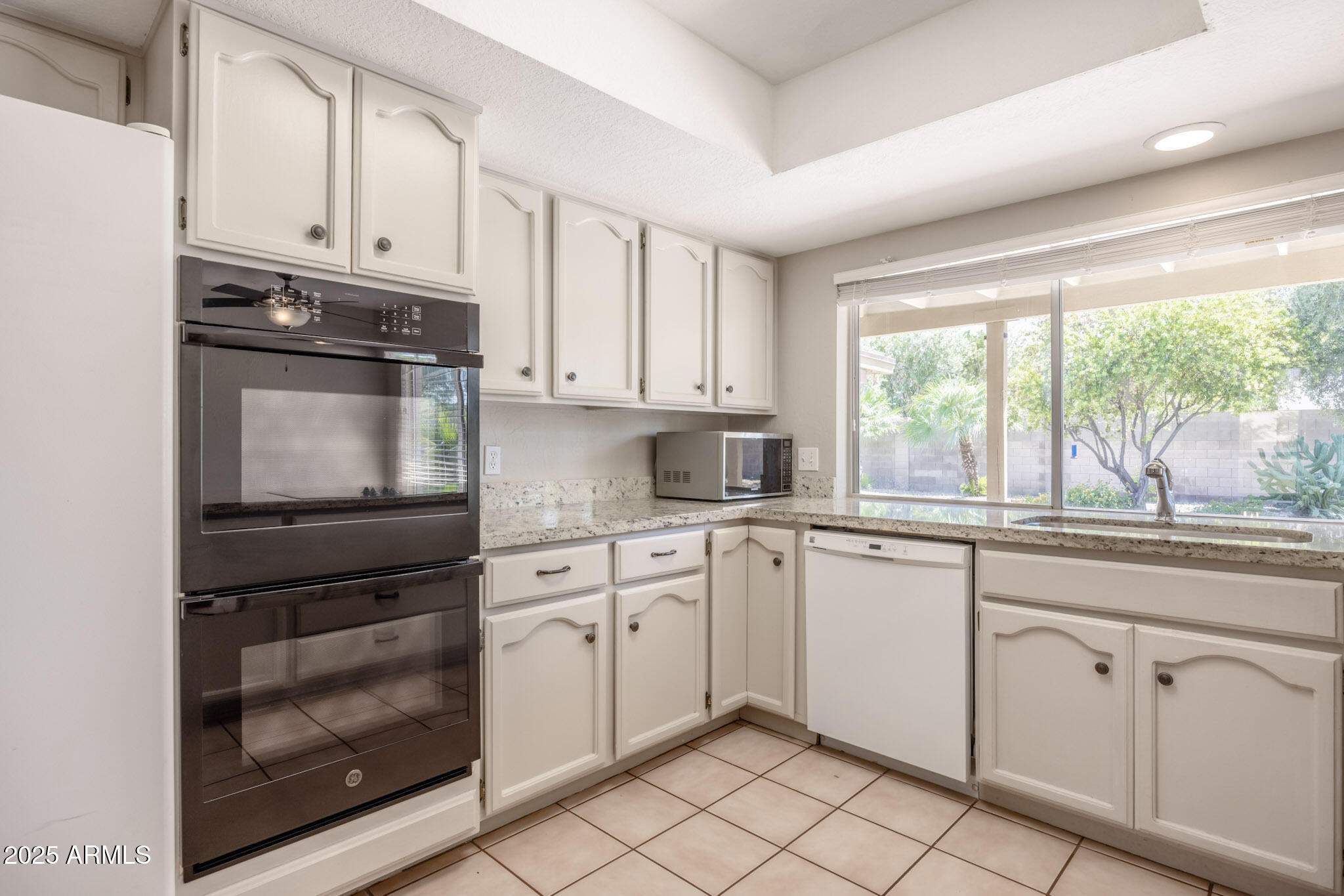 5701 East Sandy Lane Scottsdale, AZ 85254 - Photo 17 of 48 a kitchen with granite countertop white cabinets and white appliances