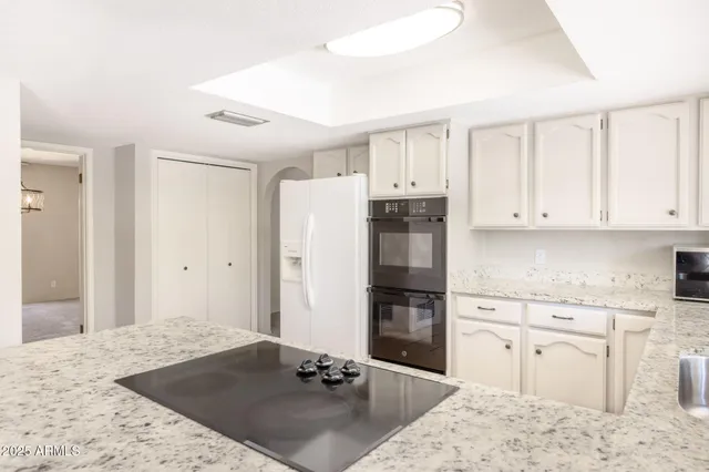 a kitchen with granite countertop a stove a sink and a refrigerator