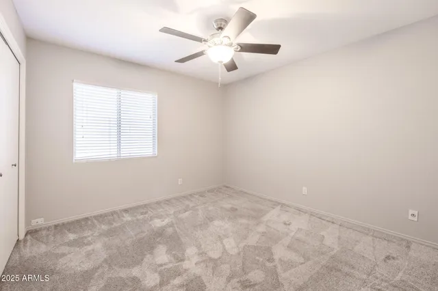 an empty room with windows and ceiling fan