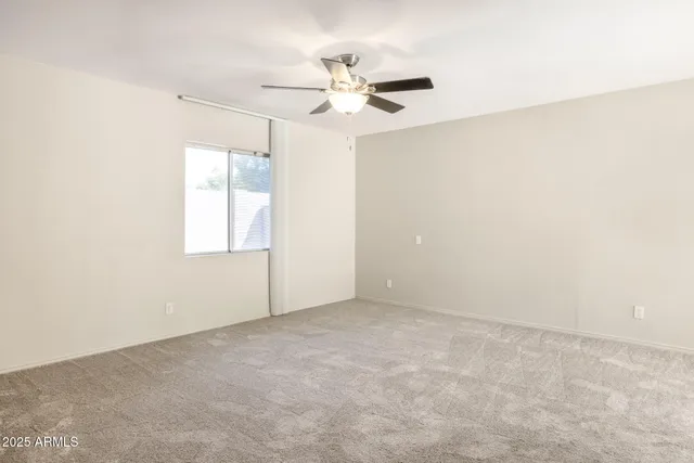 an empty room with windows and fan