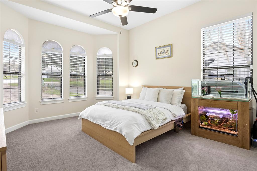 11325 Preston Cove Road Clermont, FL 34711 - Photo 38 of 58 a spacious bedroom with a bed a window and a chandelier