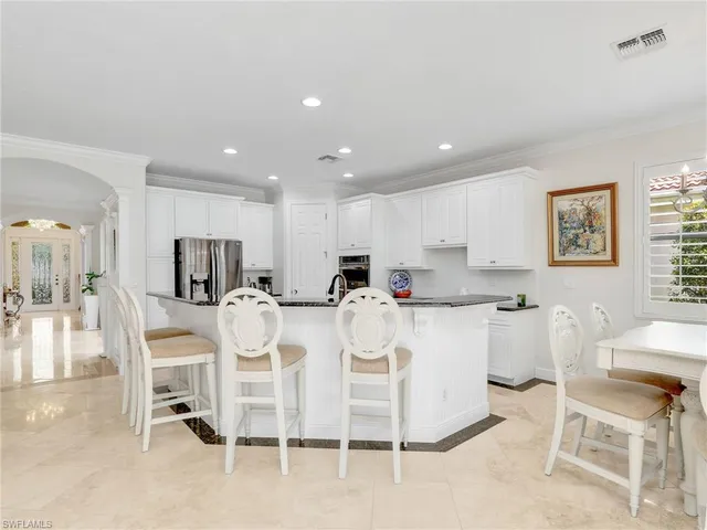 a large white kitchen with white cabinets and chairs