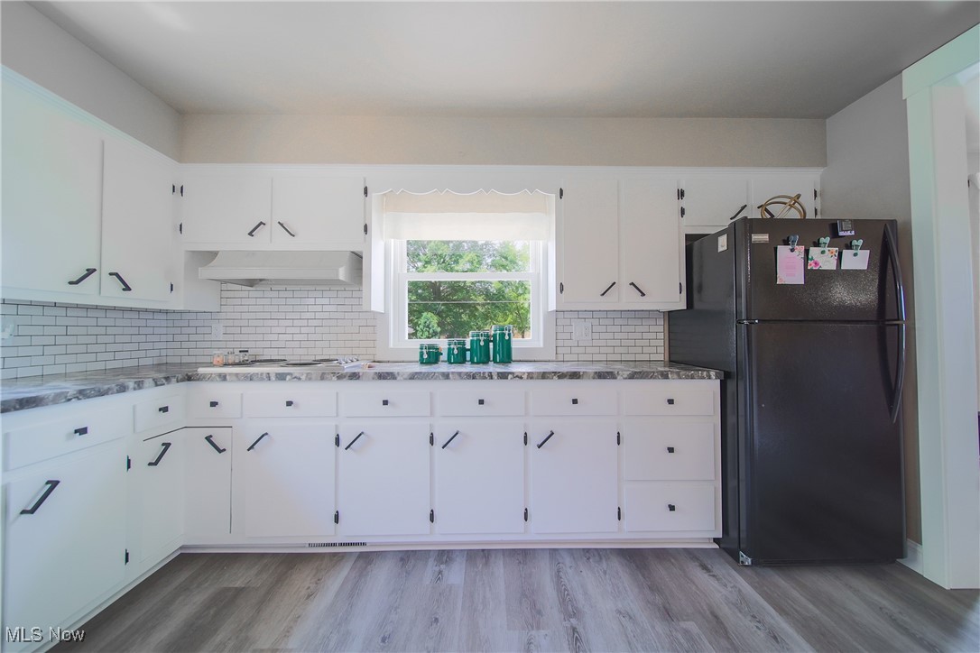 3181 Dover Road Wooster, OH 44691 - Photo 10 of 25 Kitchen featuring light hardwood / wood-style flooring, white cabinets, custom range hood, black refrigerator, and backsplash