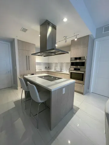 a kitchen with a stove a refrigerator and chairs