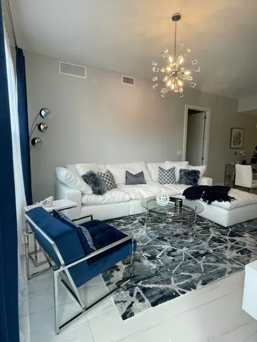 a living room with dining table and a chandelier