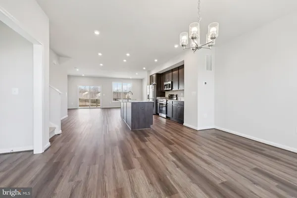 a view of a livingroom with wooden floor and a kitchen