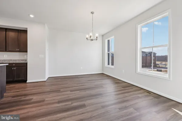 an empty room with wooden floor chandelier and windows