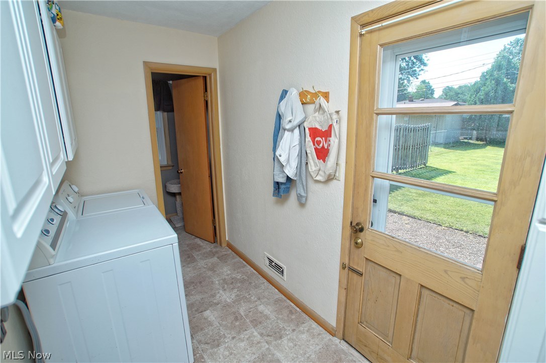 8601 Royal Ridge Drive Parma, OH 44129 - Photo 24 of 33 Utility room with white cabinets and vinyl flooring leading to half bath and back door.