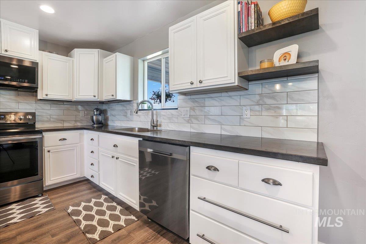 4076 North 3446 East Kimberly, ID 83341 - Photo 12 of 45 Kitchen with stainless steel appliances, open shelves, dark wood-style floors, backsplash, and white cabinetry