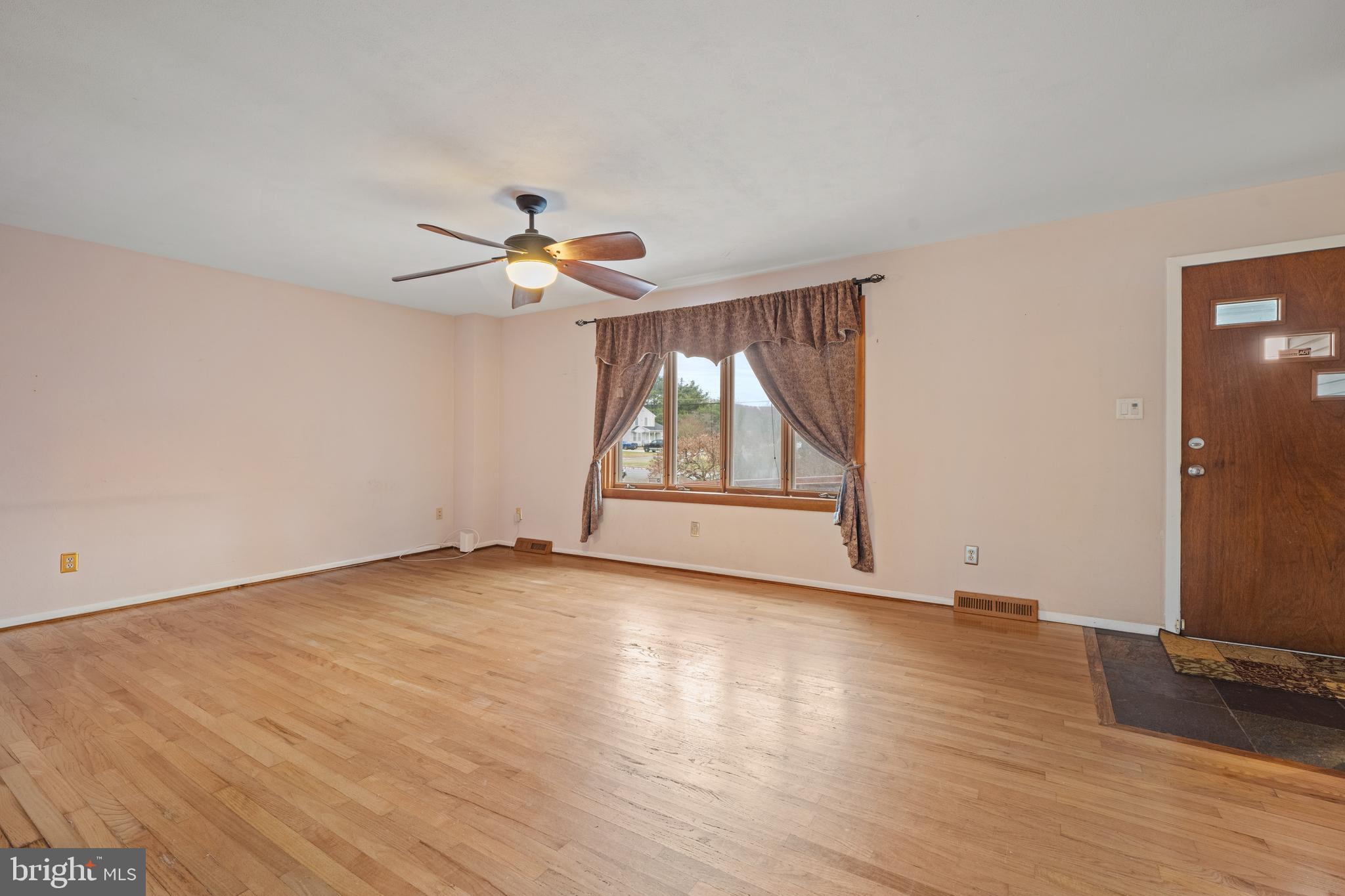 866 North Brewster Road Vineland, NJ 08361 - Photo 13 of 46 an empty room with wooden floor chandelier fan and windows