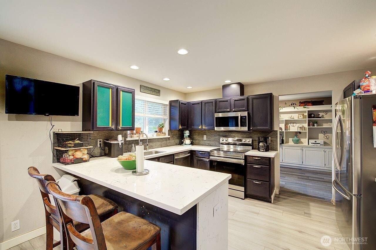 44212 Fir Road Gold Bar, WA 98251 - Photo 11 of 34 a kitchen with a stove a refrigerator and a dining table with wooden floor