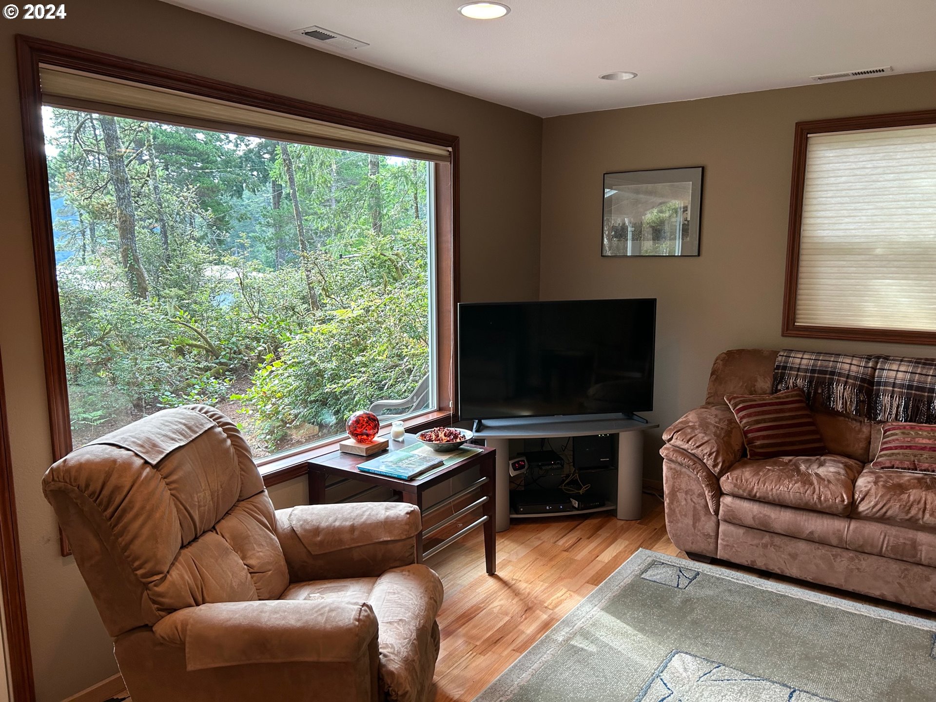 87179 Munsel Lake Road Florence, OR 97439 - Photo 7 of 27 a living room with furniture a flat screen tv and a floor to ceiling window