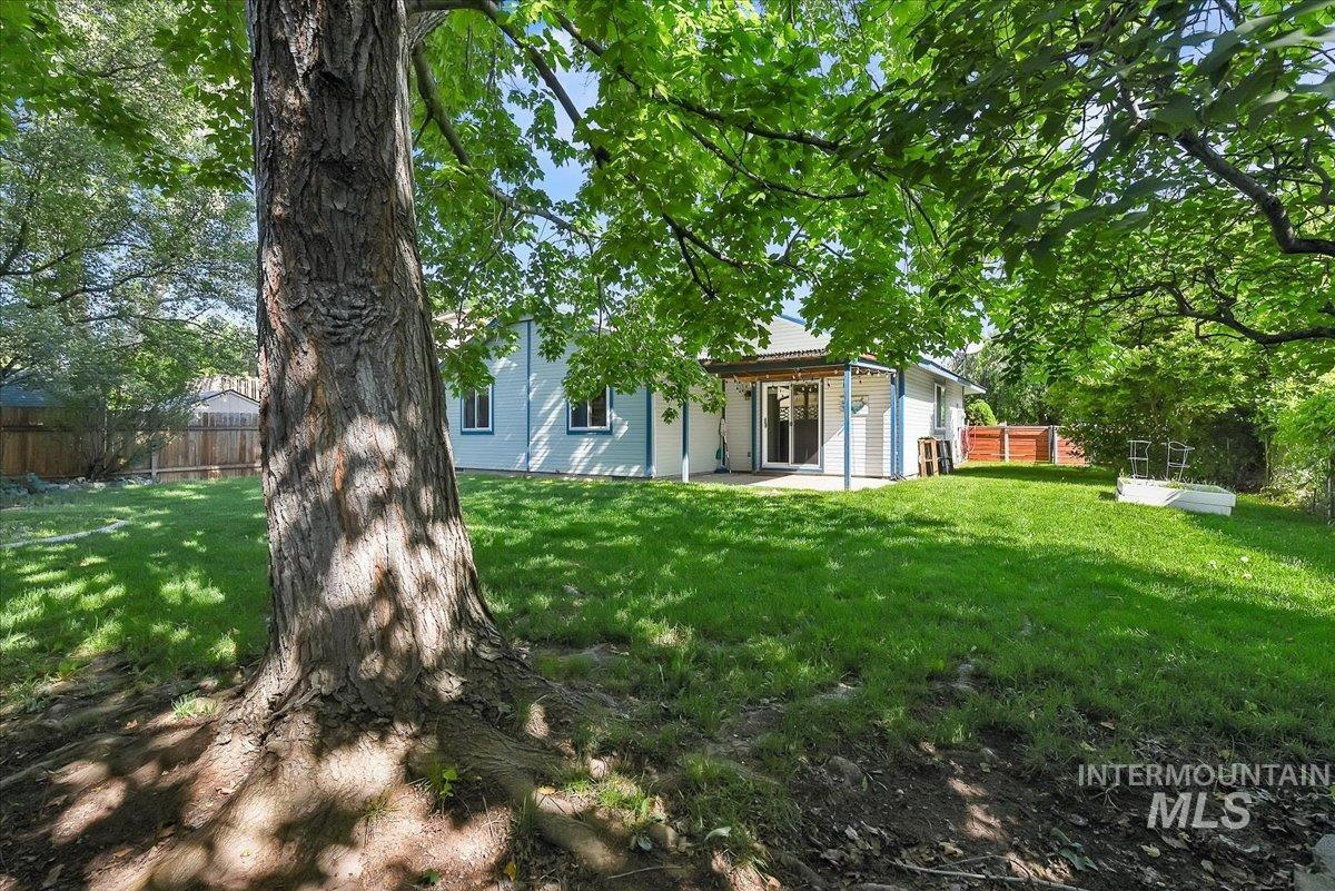 9215 West Preece Street Boise, ID 83704 - Photo 20 of 22 Expansive backyard featuring a mature tree, manicured lawn, and a covered patio with direct access to the interior