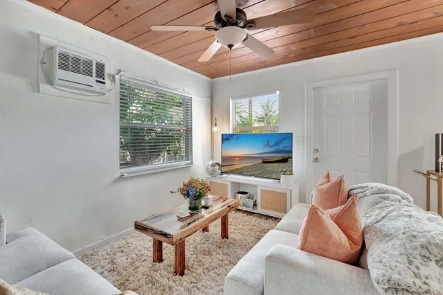 a living room with furniture a flat screen tv and a window