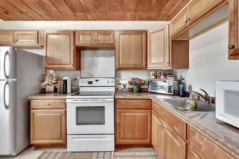 a kitchen with granite countertop white cabinets and white appliances