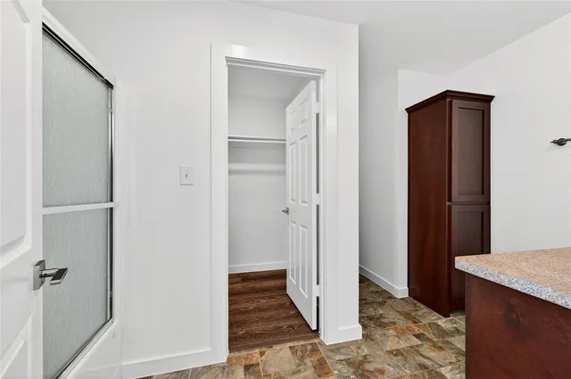 a view of a hallway with wooden floor and a bathroom