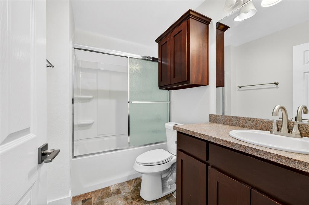 704 East Sycamore Street Sherman, TX 75090 - Photo 25 of 32 a bathroom with a granite countertop sink toilet a mirror and shower