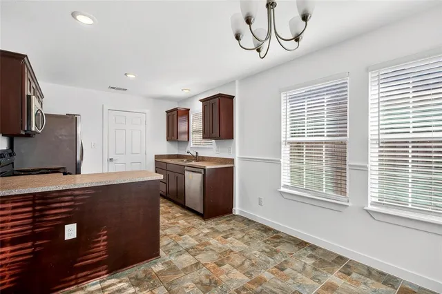 a kitchen with stainless steel appliances granite countertop a sink a stove a refrigerator cabinets and a window