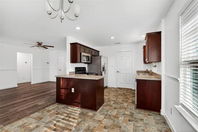 a kitchen with stainless steel appliances granite countertop a refrigerator and a stove top oven