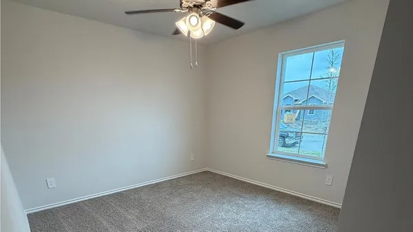 an empty room with windows and fan