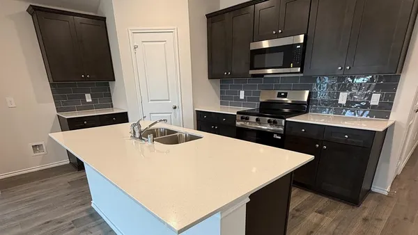 a kitchen with kitchen island a sink a stove a microwave and wooden cabinets