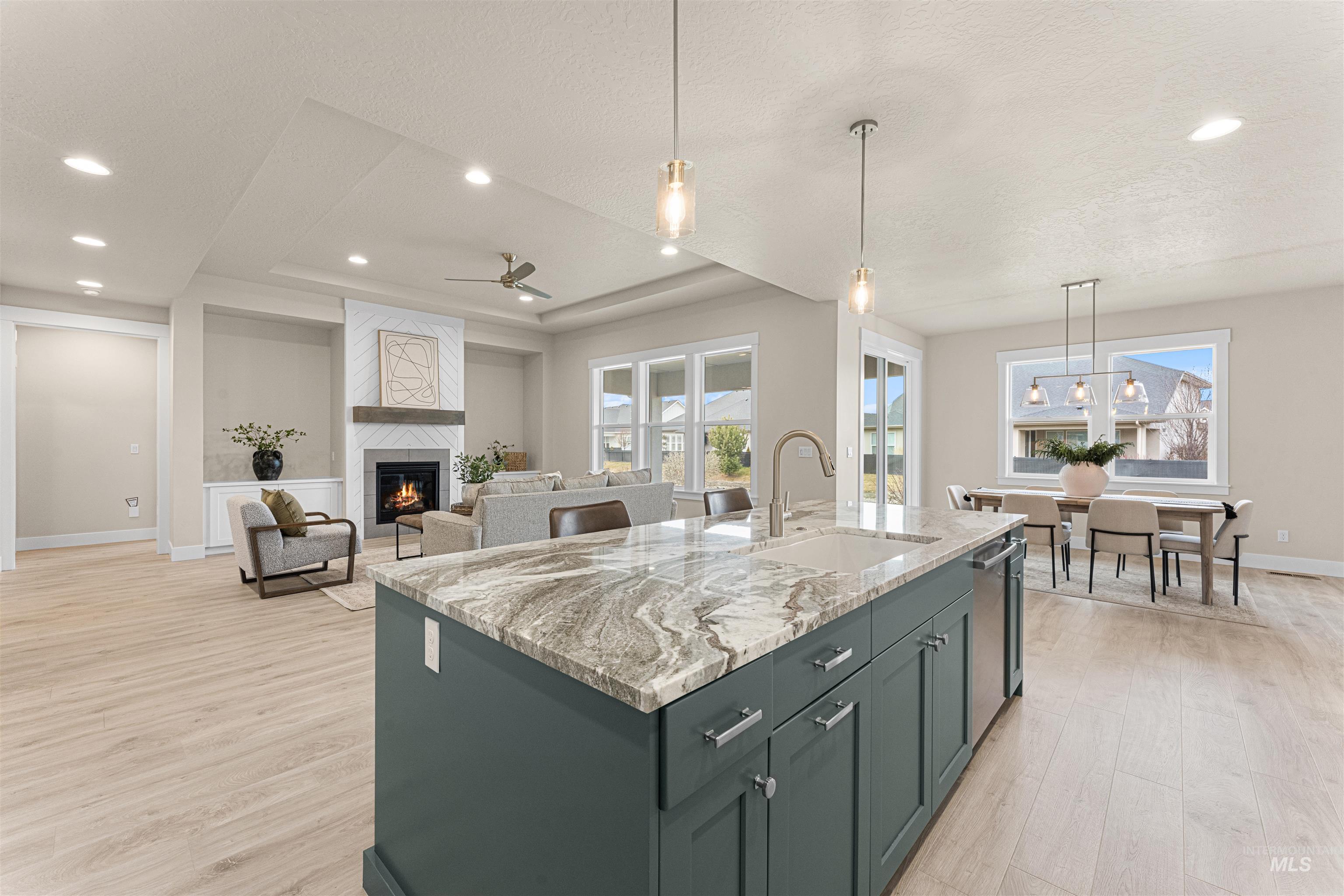 8078 Tandy Cv Street Middleton, ID 83644 - Photo 11 of 40 Kitchen with a large fireplace, hanging light fixtures, a ceiling fan, light stone countertops, and light wood-style flooring