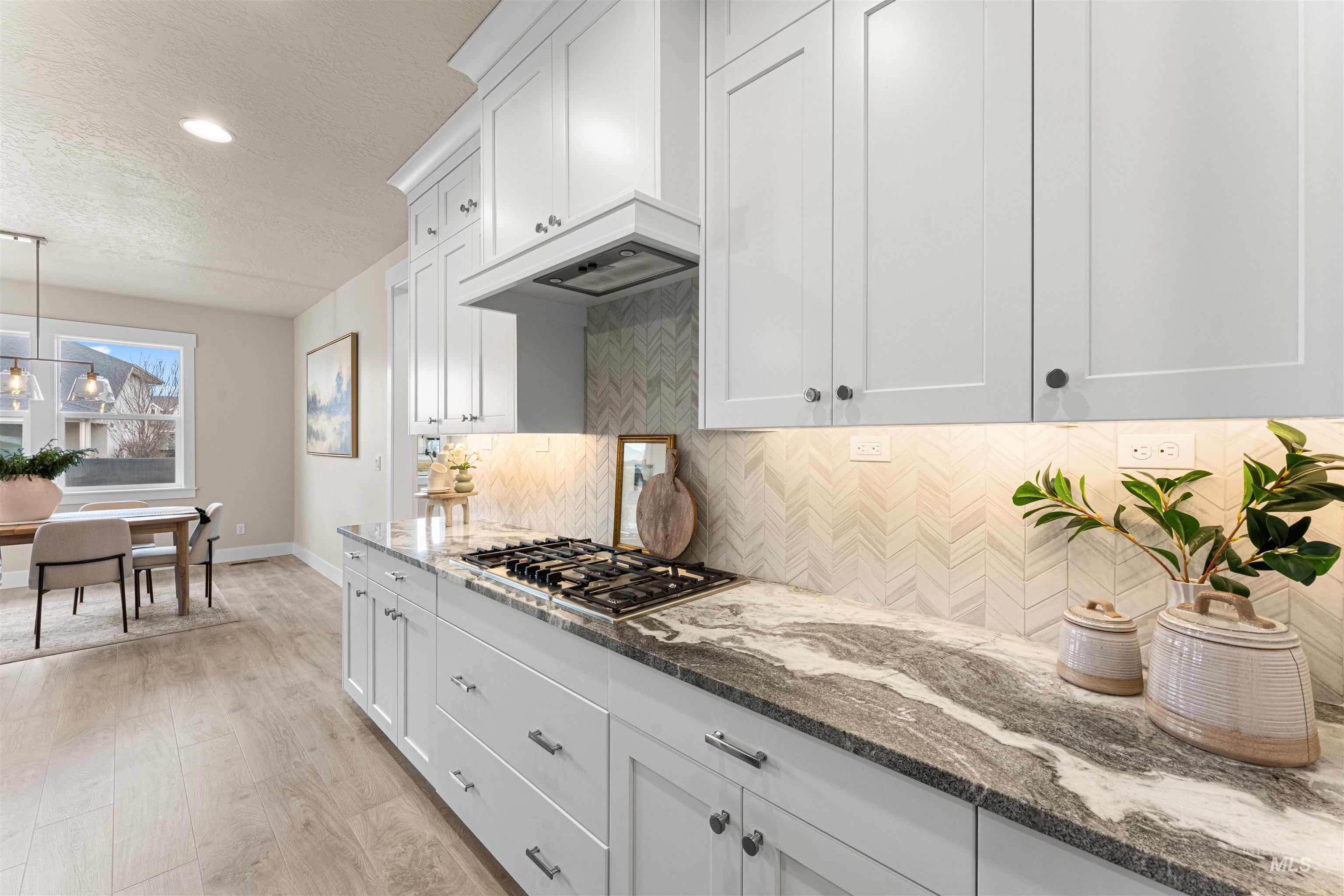 8078 Tandy Cv Street Middleton, ID 83644 - Photo 12 of 40 Kitchen with dark stone counters, white cabinetry, light wood-style floors, a textured ceiling, and hanging light fixtures