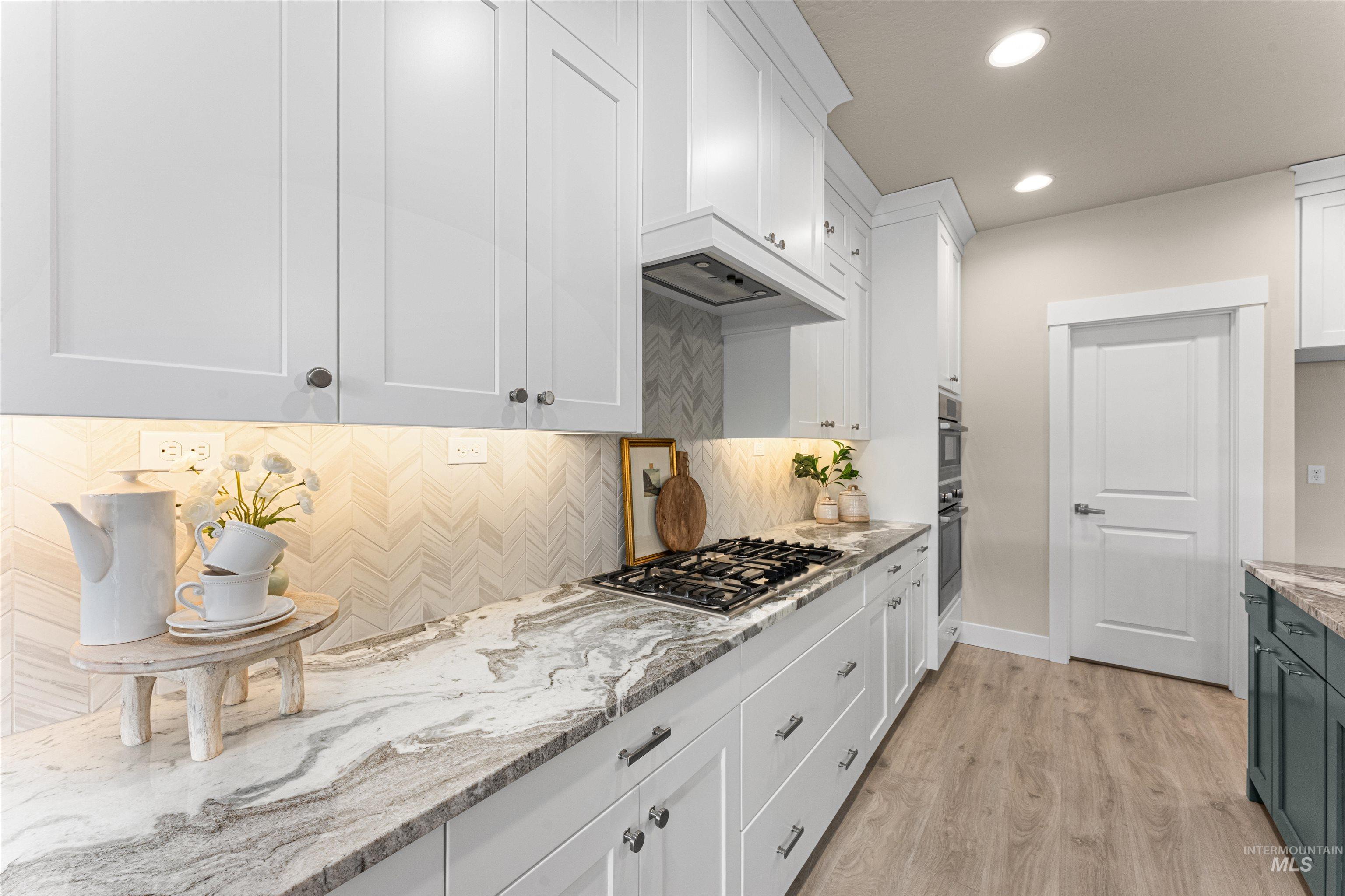 8078 Tandy Cv Street Middleton, ID 83644 - Photo 13 of 40 Kitchen with light stone countertops, light wood-type flooring, recessed lighting, stainless steel gas cooktop, and decorative backsplash