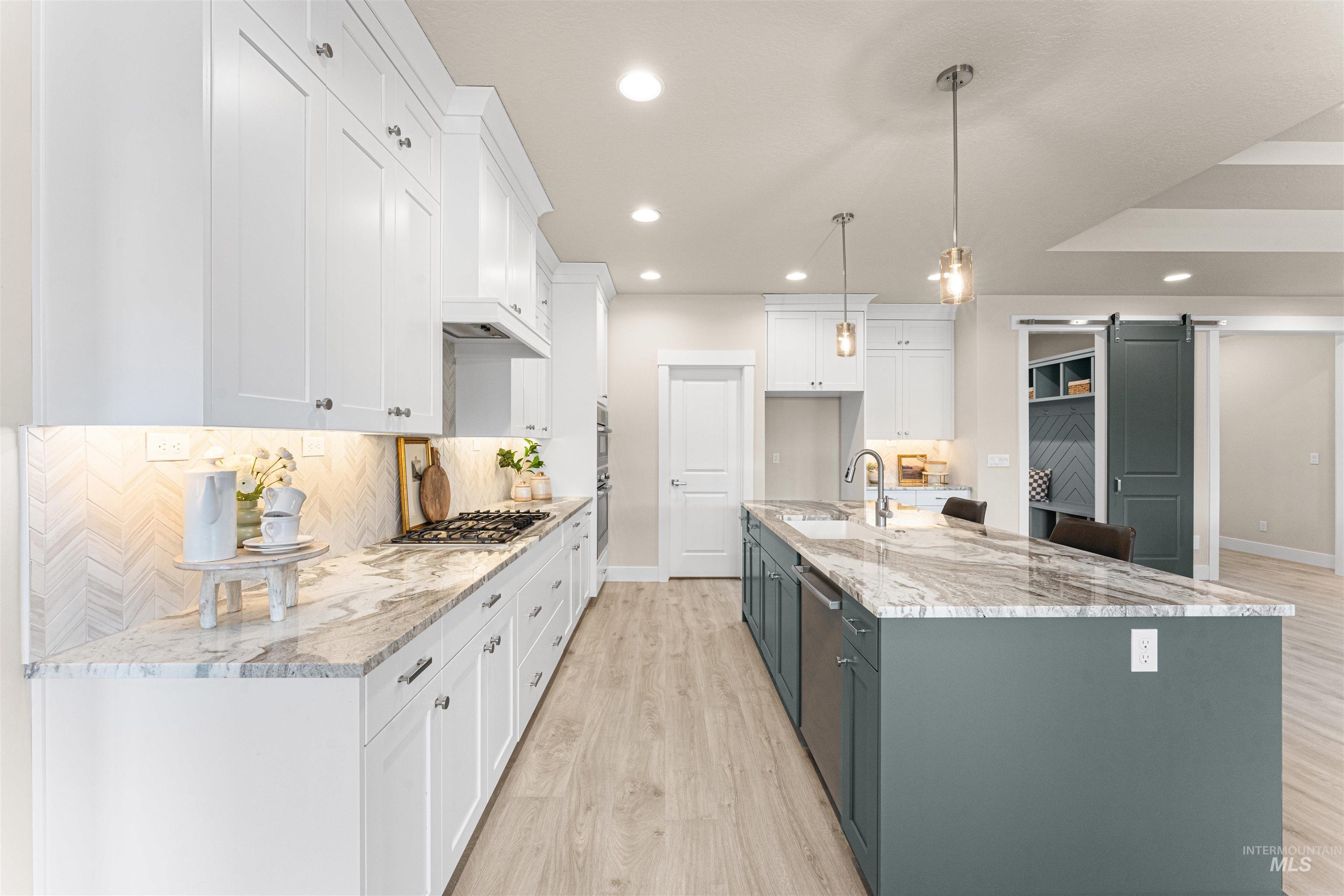 8078 Tandy Cv Street Middleton, ID 83644 - Photo 14 of 40 Two tone kitchen featuring two tone color scheme, a barn door, light wood-type flooring, light stone countertops, and hanging light fixtures