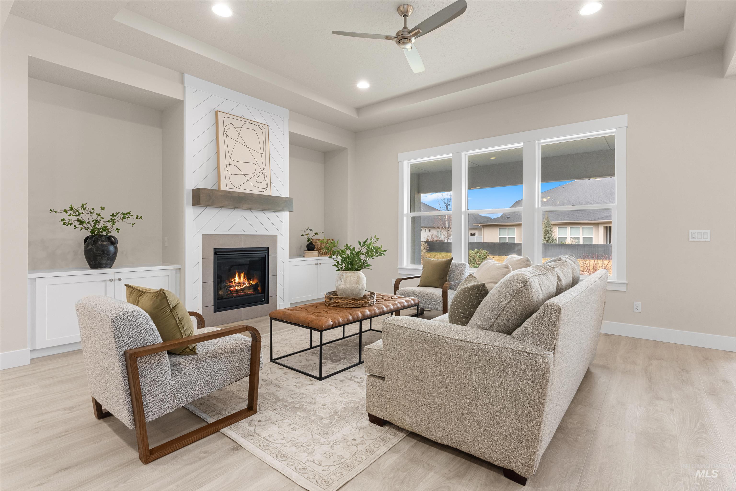 8078 Tandy Cv Street Middleton, ID 83644 - Photo 2 of 40 Living area featuring a tray ceiling, ceiling fan, a tiled fireplace, light wood-type flooring, and recessed lighting