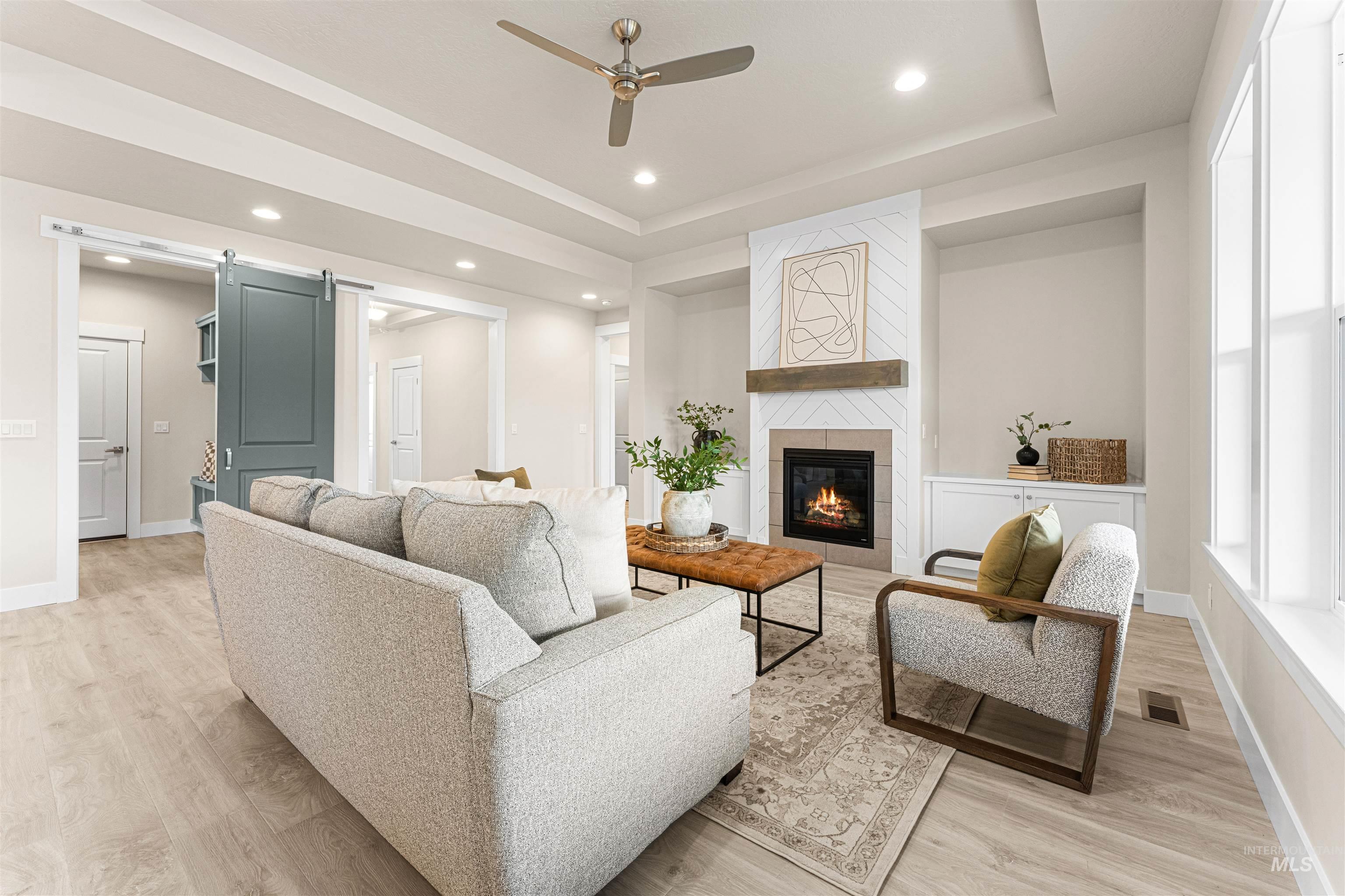 8078 Tandy Cv Street Middleton, ID 83644 - Photo 4 of 40 Living area with a barn door, ceiling fan, light wood-style floors, recessed lighting, and a tray ceiling