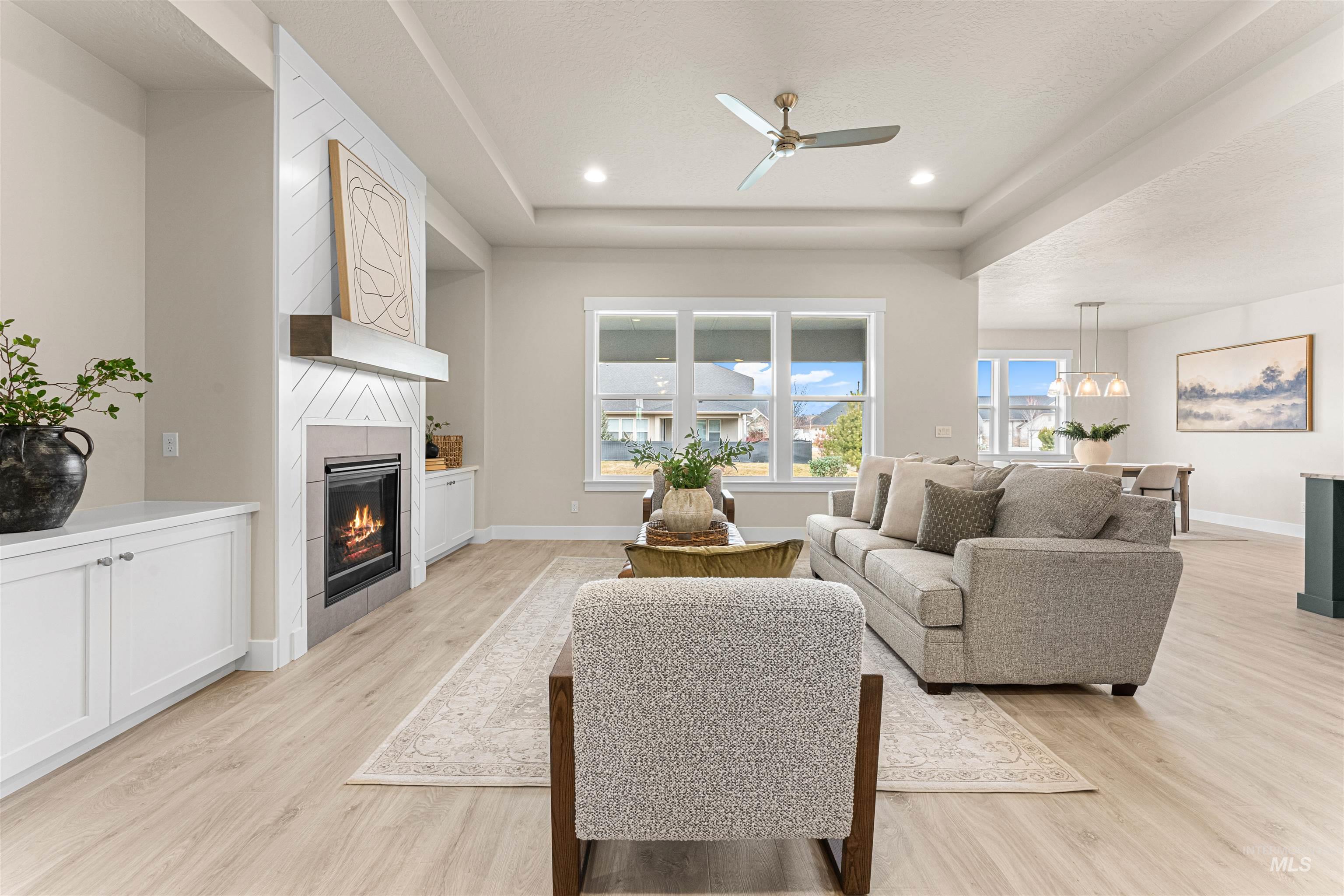 8078 Tandy Cv Street Middleton, ID 83644 - Photo 5 of 40 Living room featuring ceiling fan, a fireplace, light wood-style flooring, a tray ceiling, and recessed lighting