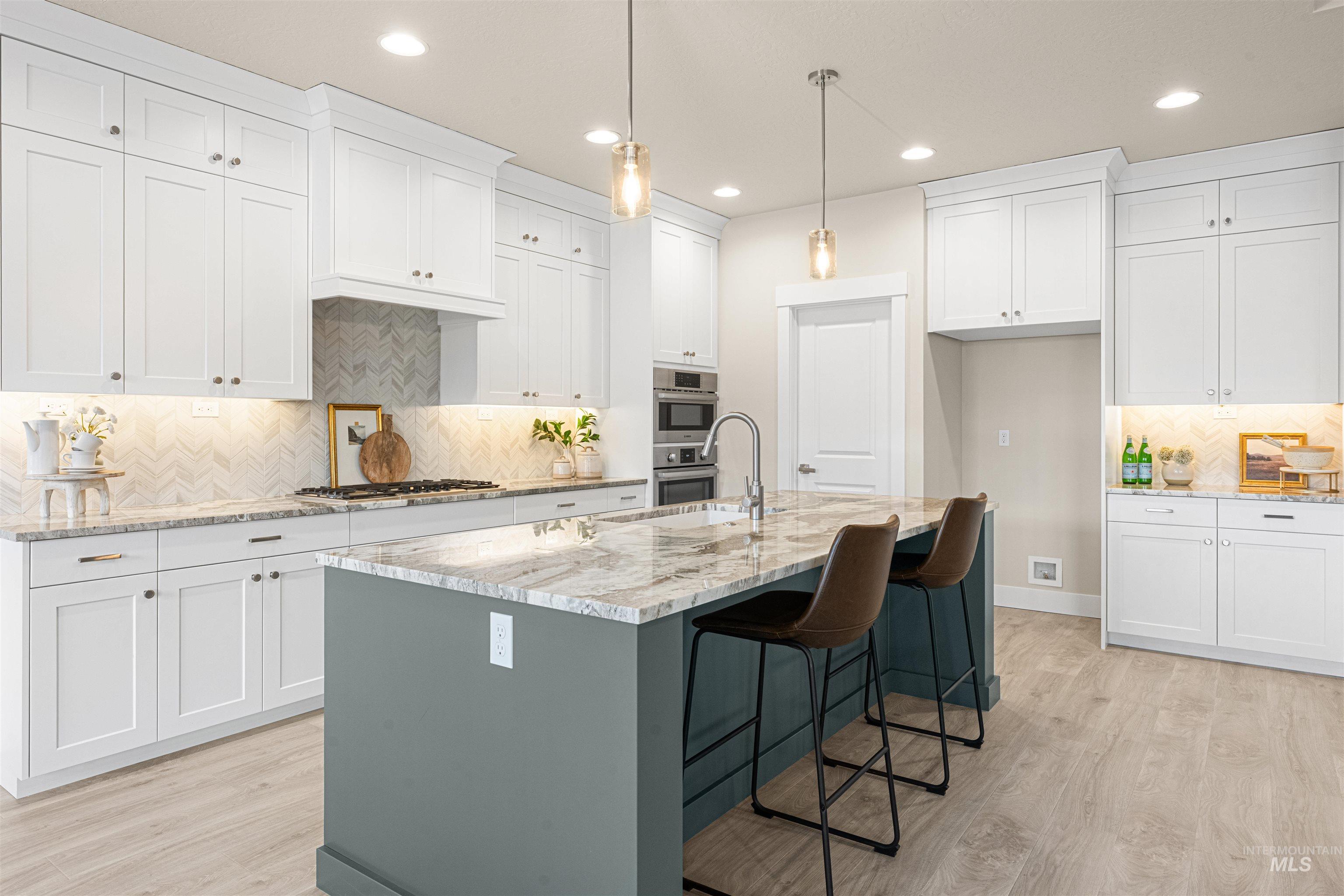 8078 Tandy Cv Street Middleton, ID 83644 - Photo 8 of 40 Kitchen featuring decorative backsplash, light wood-type flooring, light stone countertops, a breakfast bar, and dual tone cabinetry