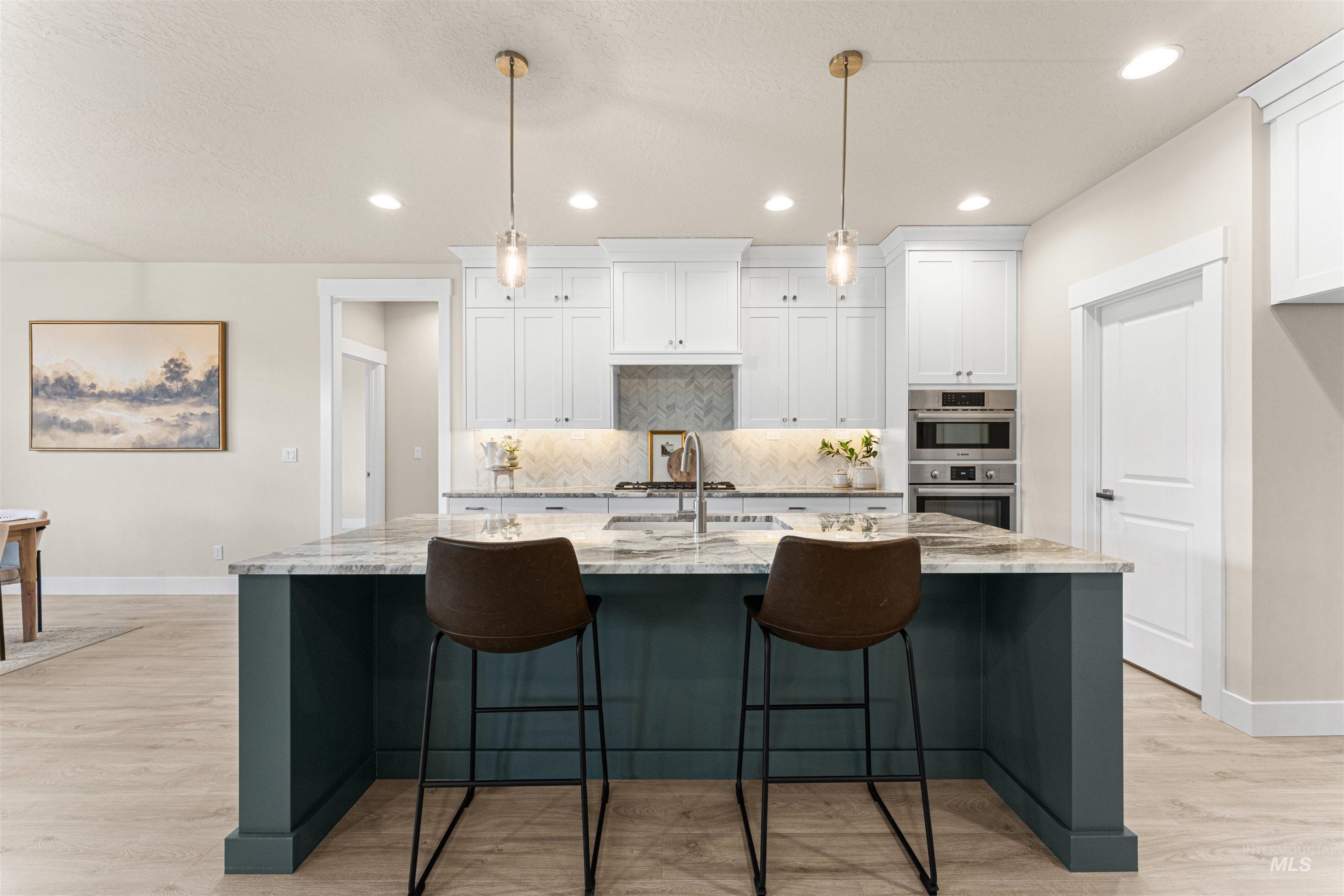 8078 Tandy Cv Street Middleton, ID 83644 - Photo 9 of 40 Kitchen with light stone countertops, hanging light fixtures, light wood-style floors, a breakfast bar area, and a center island with sink
