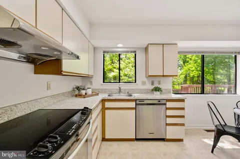 a kitchen with stainless steel appliances a refrigerator a stove a dining table and chairs with wooden floor