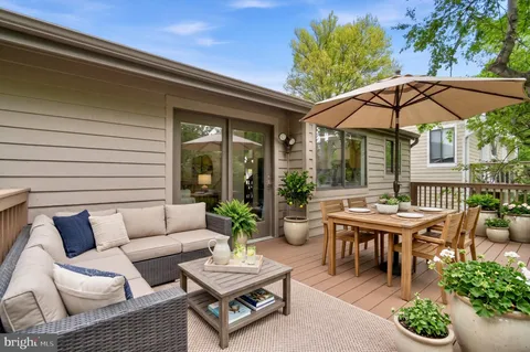 a view of a patio with couches table and chairs under an umbrella