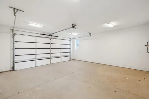 an empty room with ceiling fan and windows