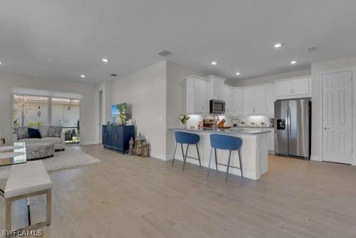 1064 Tranquil Brook Drive Naples, FL 34114 - Photo 2 of 28 a open kitchen with stainless steel appliances kitchen island granite countertop a couch and a refrigerator