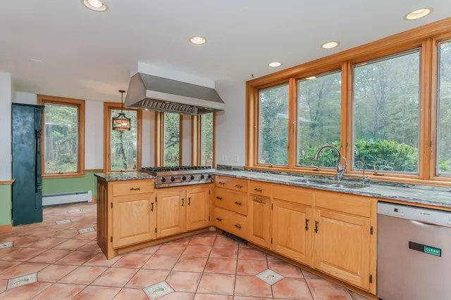 a large white kitchen with granite countertop a large window and white stainless steel appliances