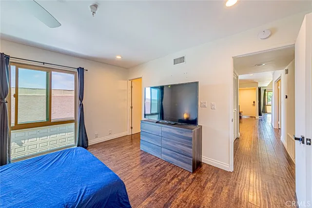 a living room with a flat screen tv on dresser and a wooden floor