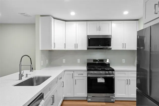 a kitchen with stainless steel appliances granite countertop a stove a sink and a microwave
