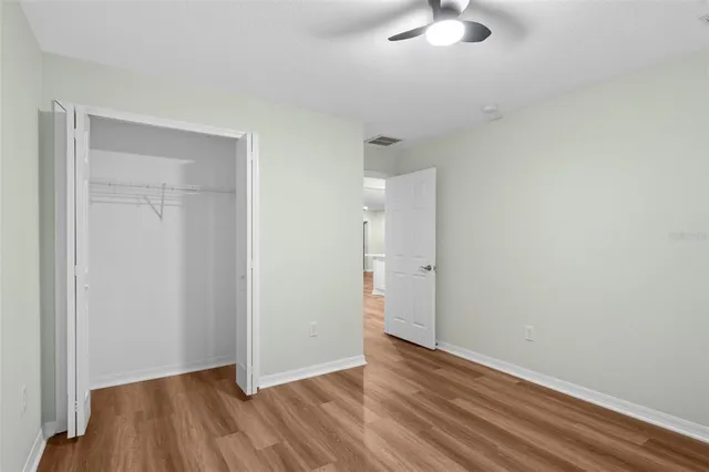 an empty room with wooden floor and chandelier fan