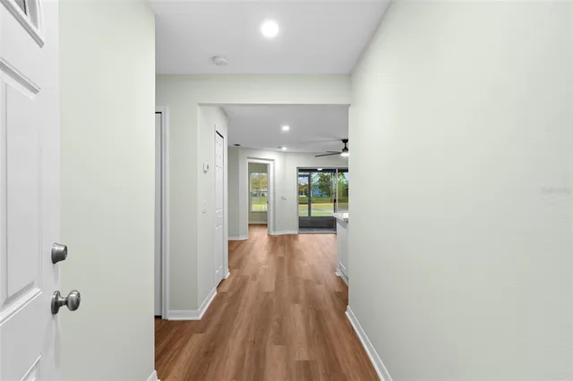 a view of a hallway with wooden floor and a bathroom