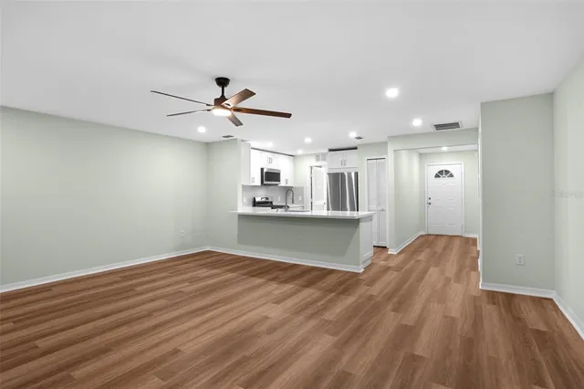 a view of kitchen and empty room with wooden floor