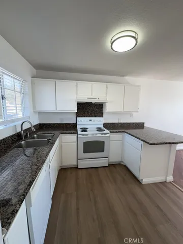 a kitchen with granite countertop a sink cabinets and stainless steel appliances