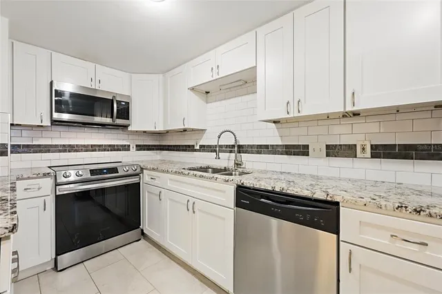 a kitchen with granite countertop white cabinets and stainless steel appliances