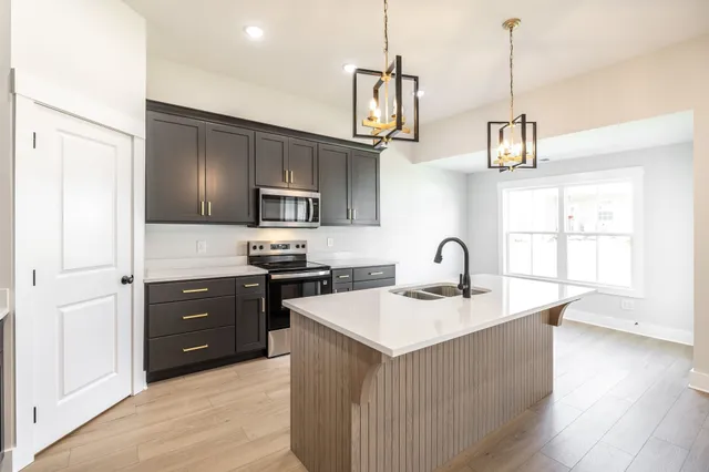 a kitchen with stainless steel appliances granite countertop a sink a stove and a refrigerator