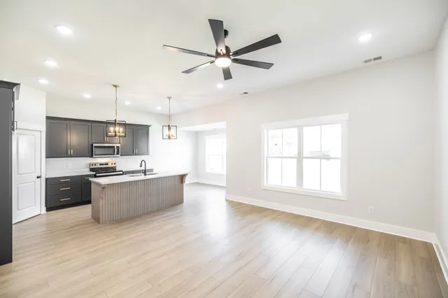 a large kitchen with a wooden floor and stainless steel appliances